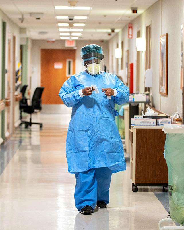 A nurse dons gloves in the hallway at Englewood Health.