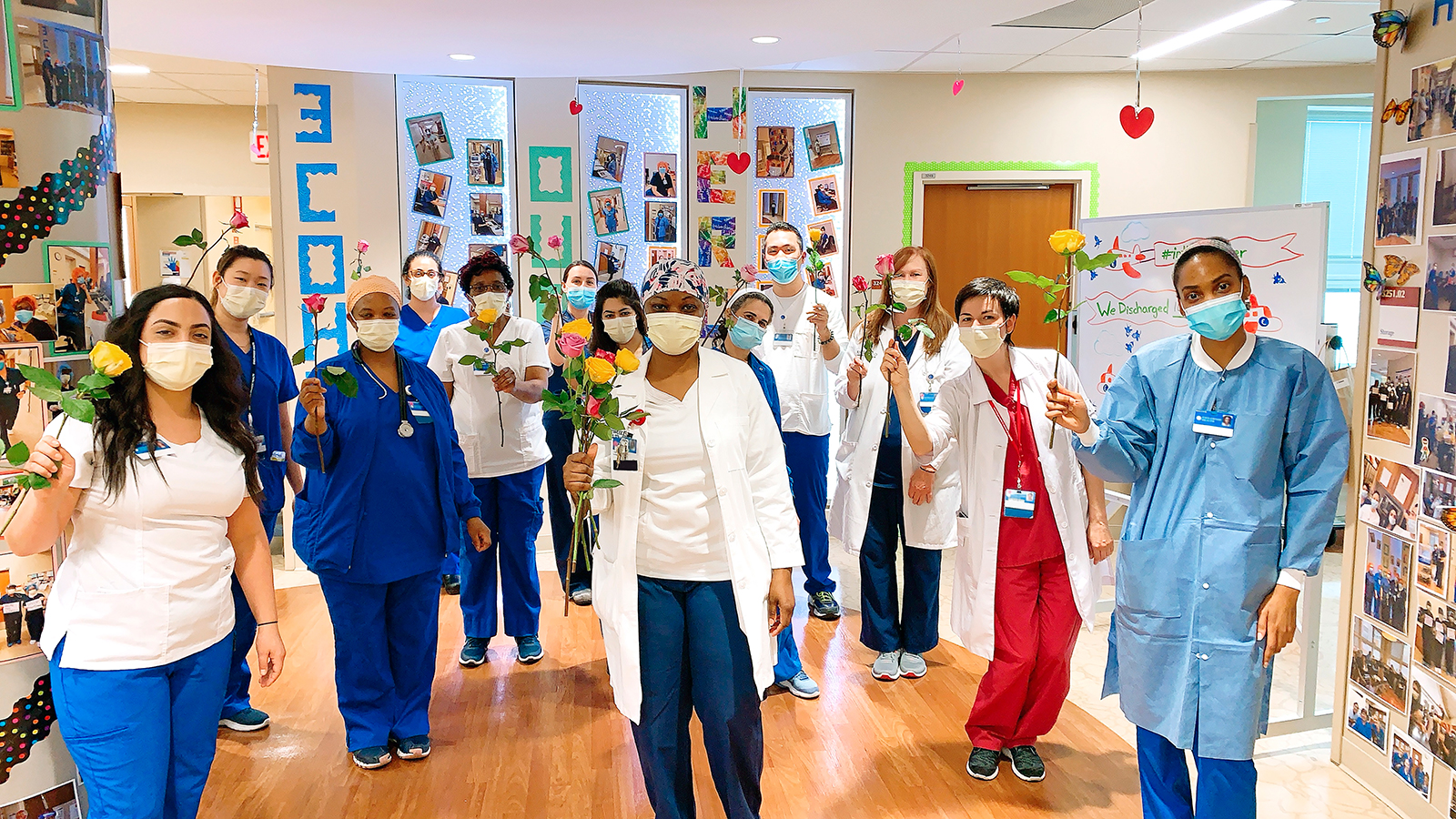 A group of doctors and nurses at Englewood Health stand together, holding roses.