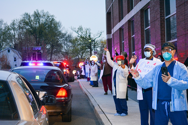 Englewood Health staff wave and hold signs of appreciation as first responders parade past the building.