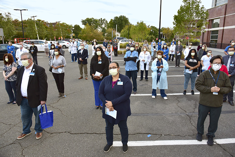 Englewood Health team members and community members stand together solemnly in the parking lot.