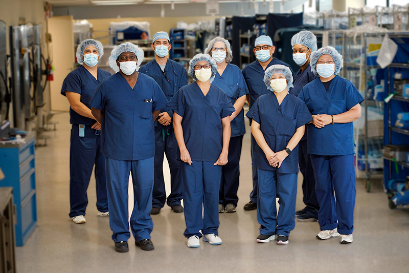 A group of Englewood Health team members in masks and hair nets stand together.